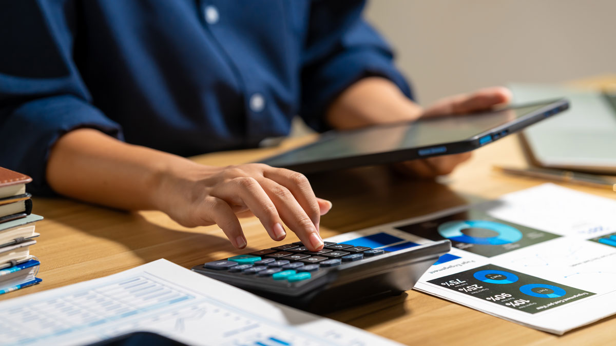 Person mit Tablet und Taschenrechner bei der Budgetplanung